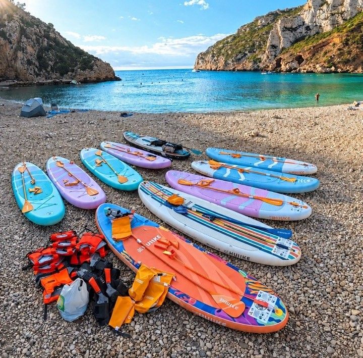 SUP-доски на пляже Cala Granadella с бирюзовой водой, скалами и красивой бухтой Коста-Бланки